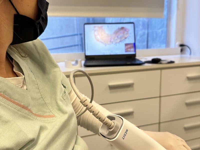 Odontóloga usando el escáner intraoral, con el modelo digital de la boca en la pantalla.